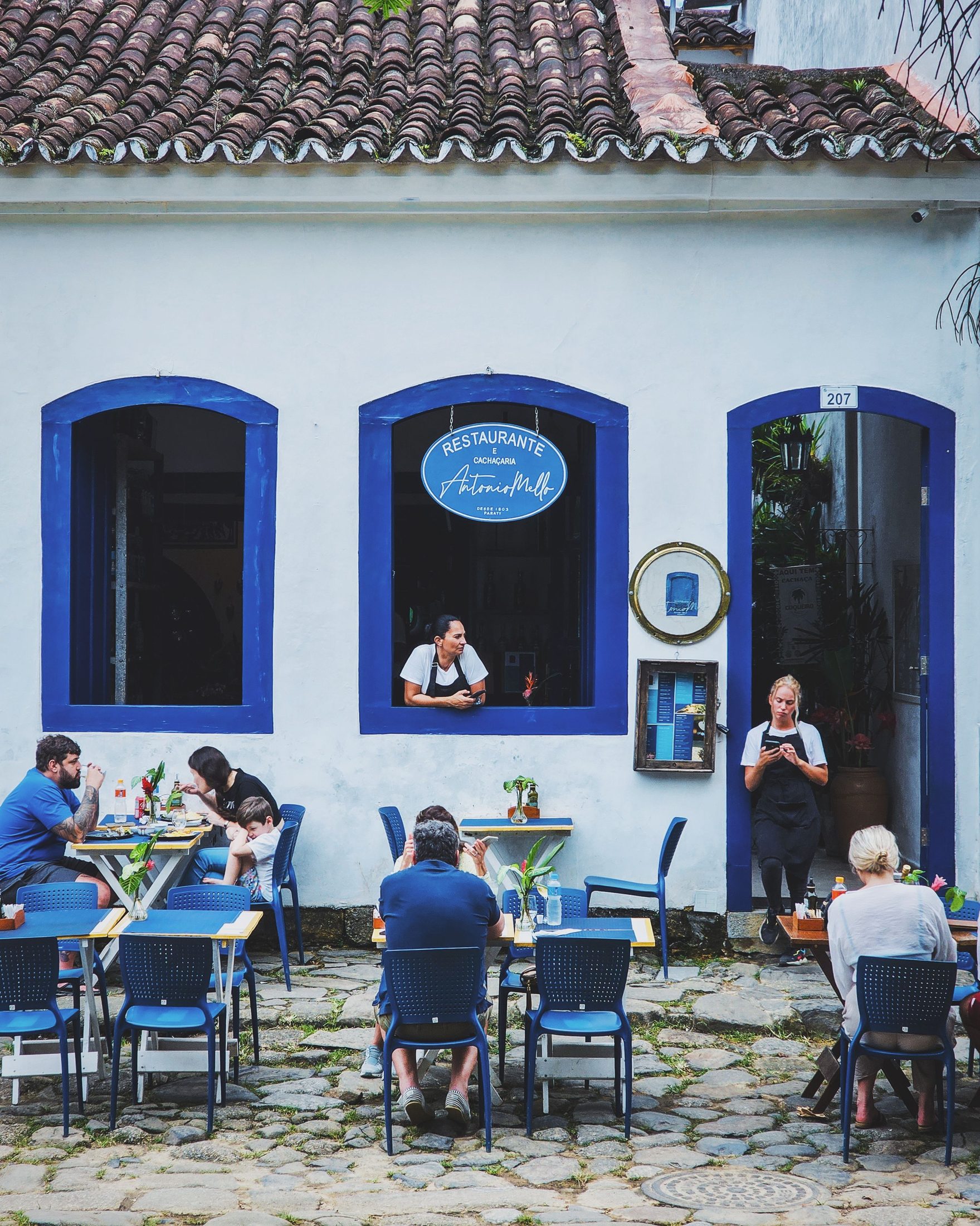 People seated outside a blue building facade.